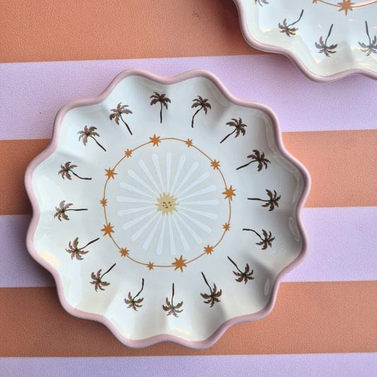 Close-up van keramisch bordje met zon en palmbomen, kleurrijk en speels, leuk voor borrelplanken of als decoratie