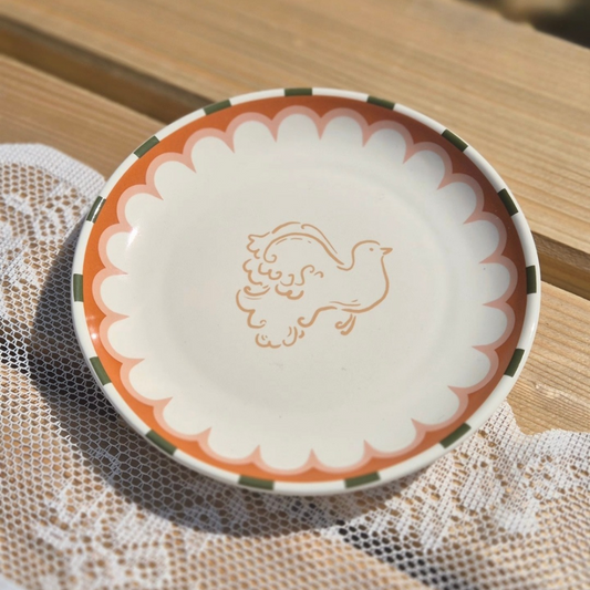 Detailfoto van dit kleurrijke bordje met oranje vogel van all the luck in the world