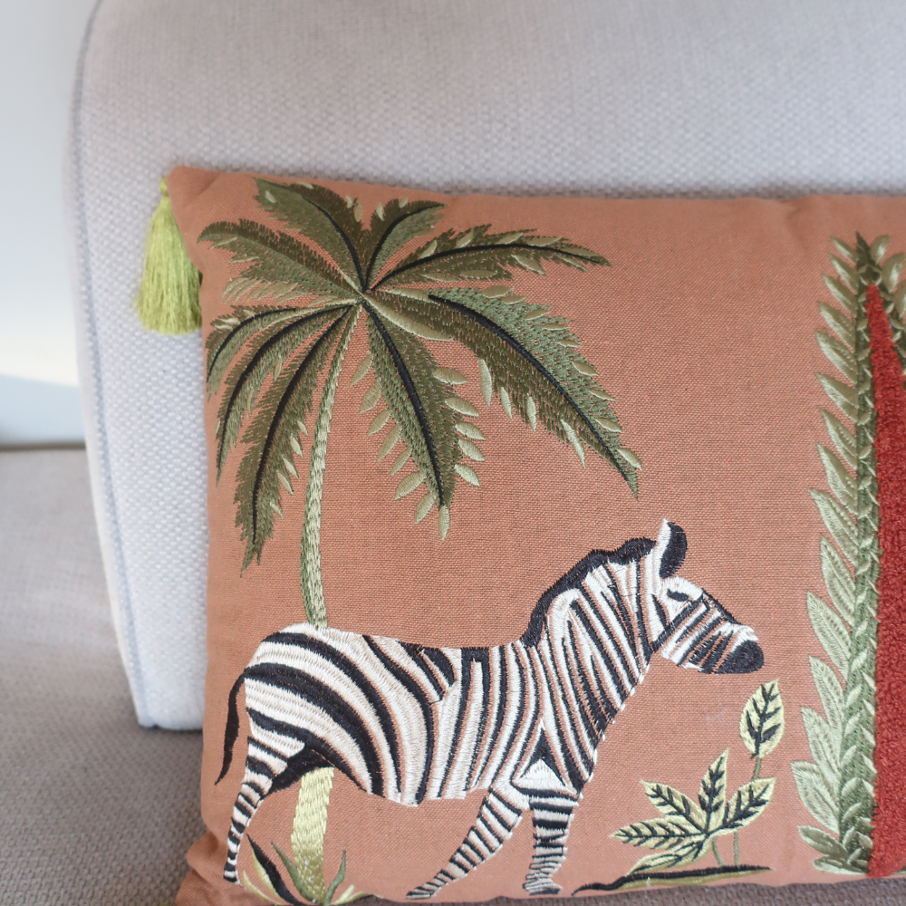Detail van de geborduurde zebra en kwastjes op Kussen Zebra sierkussen als uniek woonaccessoire