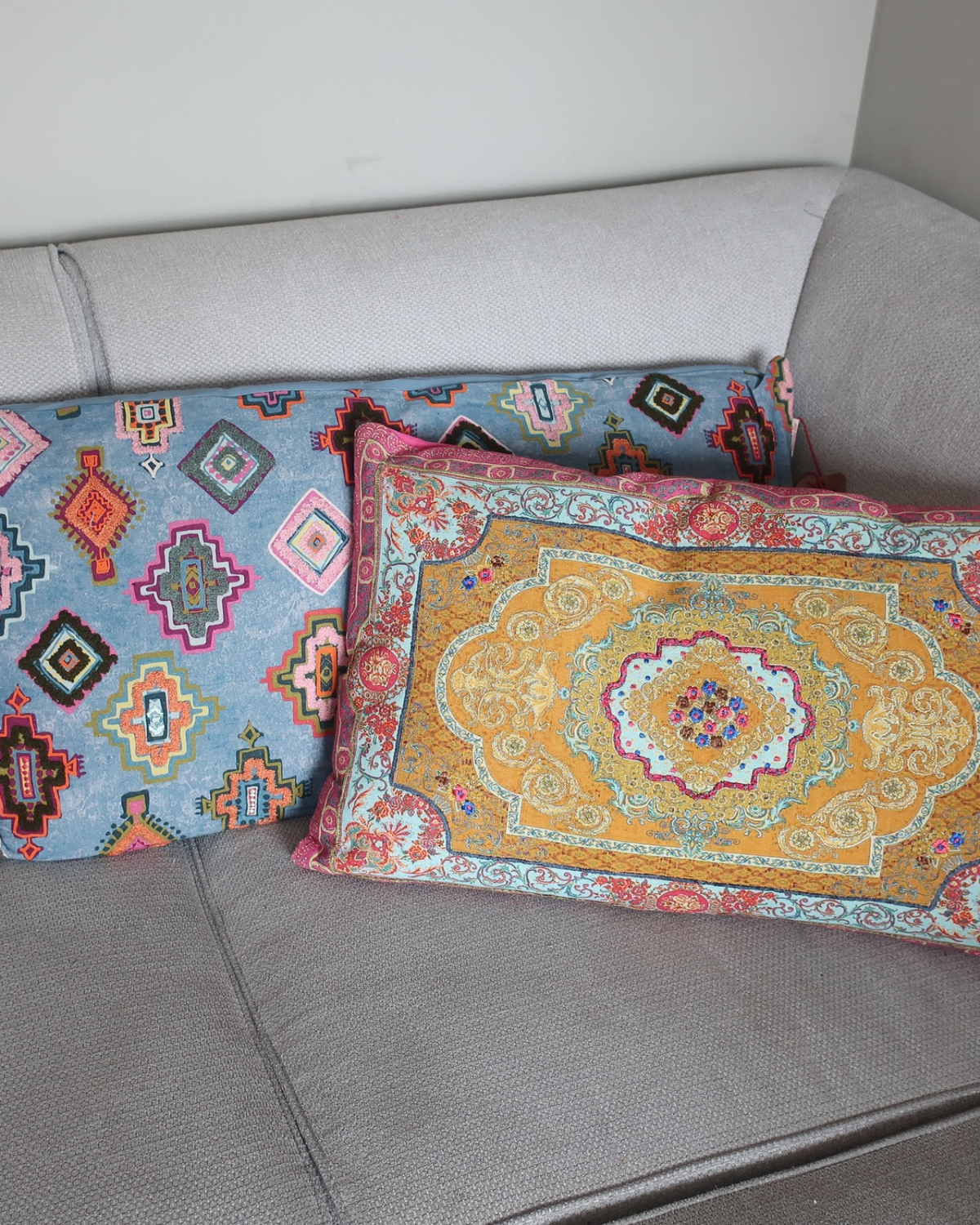 Kussen Vidya in frisse kleuren mosterdgeel, babyblauw en magenta, gestyled op bank als decoratief woonaccessoire