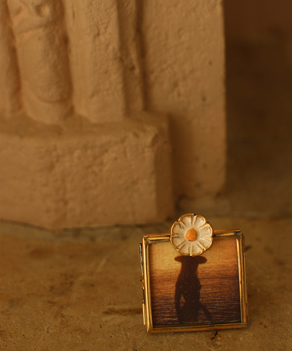 Close-up van dit handgemaakte mini fotolijstje van gerecycled messing en glas met vrolijk madeliefje. Perfect om kleine herinneringen te koesteren.